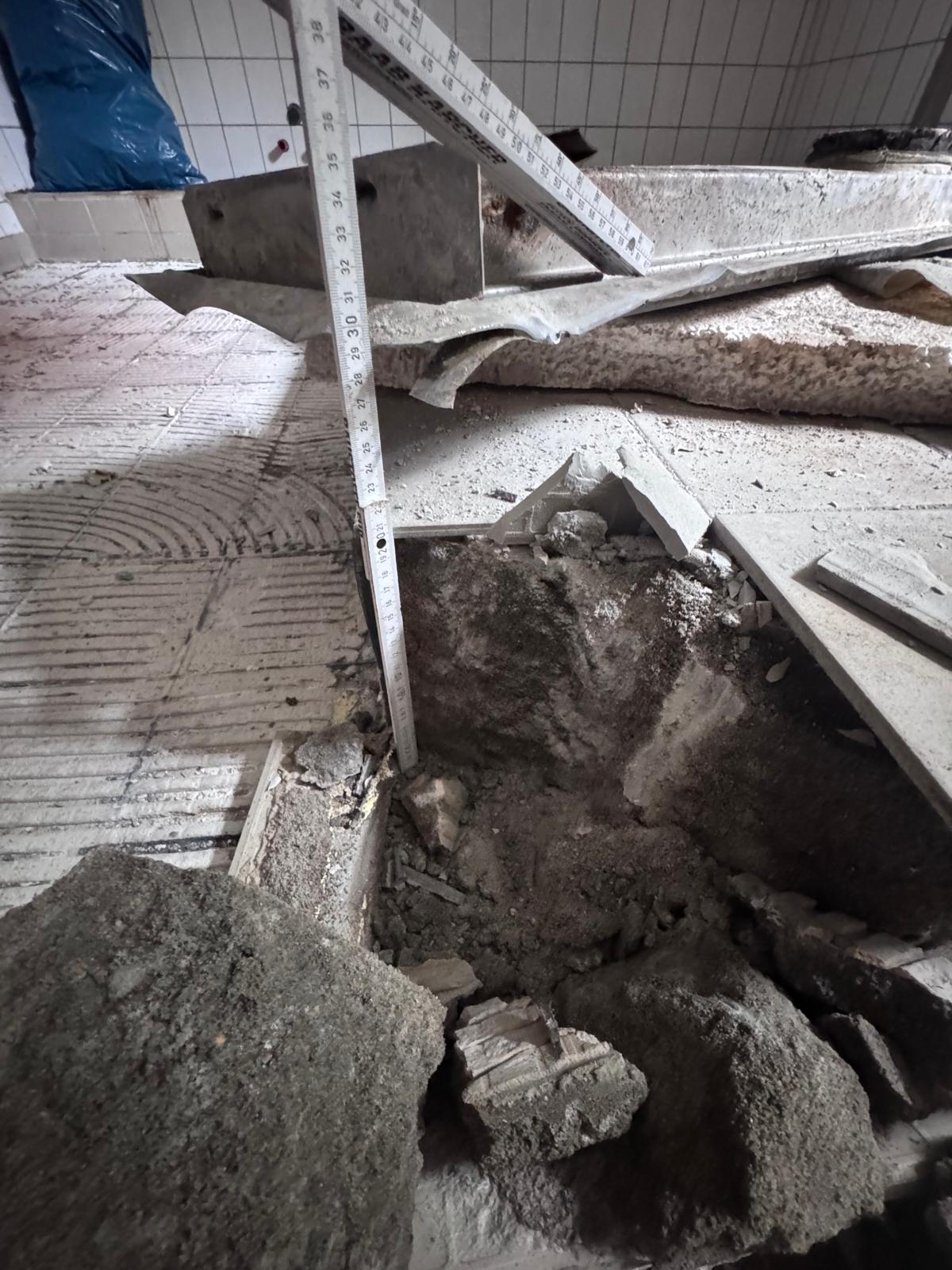 Geöffneter Estrichaufbau in einer Gewerbeküche mit Maßstab zur Prüfung der Aufbauhöhe
