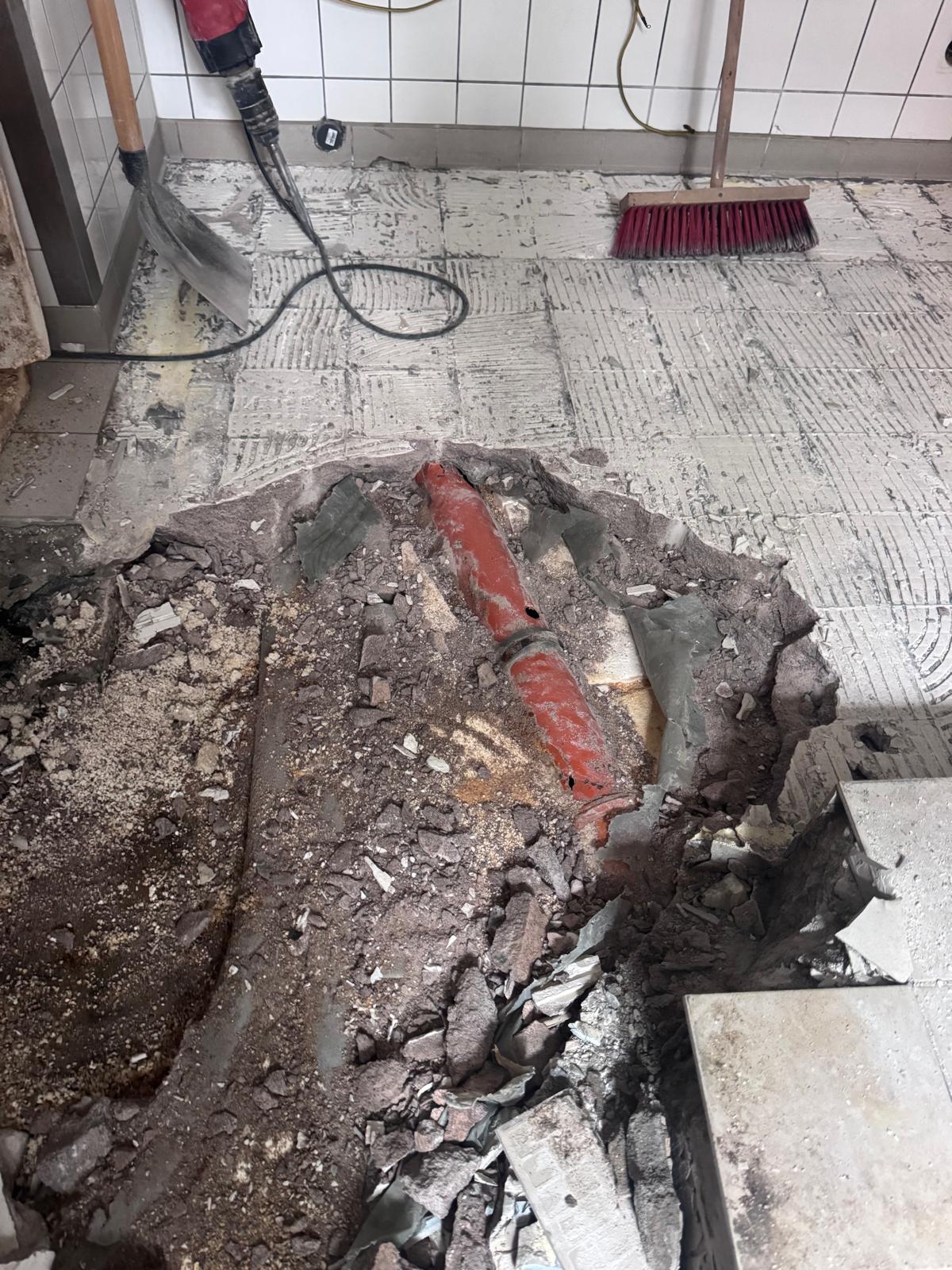 Freigelegte rote Abwasserleitung unter dem Boden einer Gewerbeküche in Magdeburg