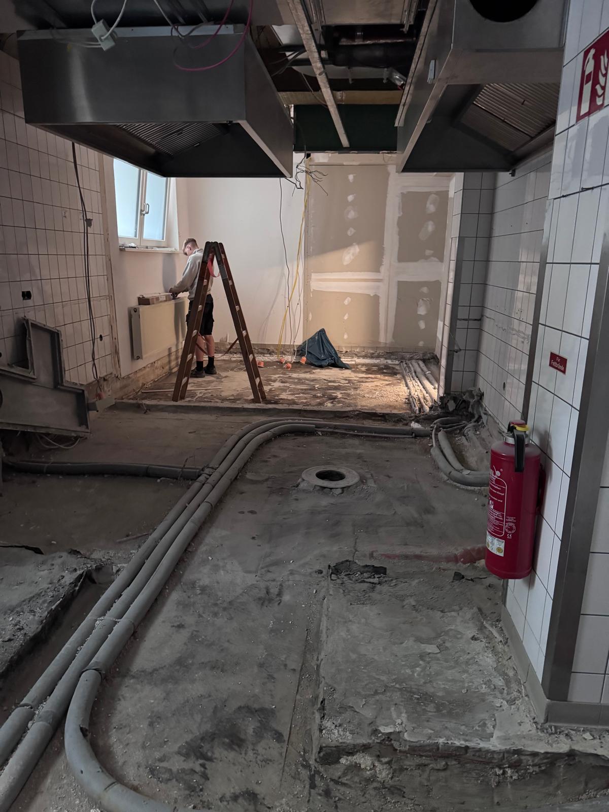 Entkernte Gewerbeküche mit freigelegten Leitungswegen und vorbereiteter Trockenbauwand