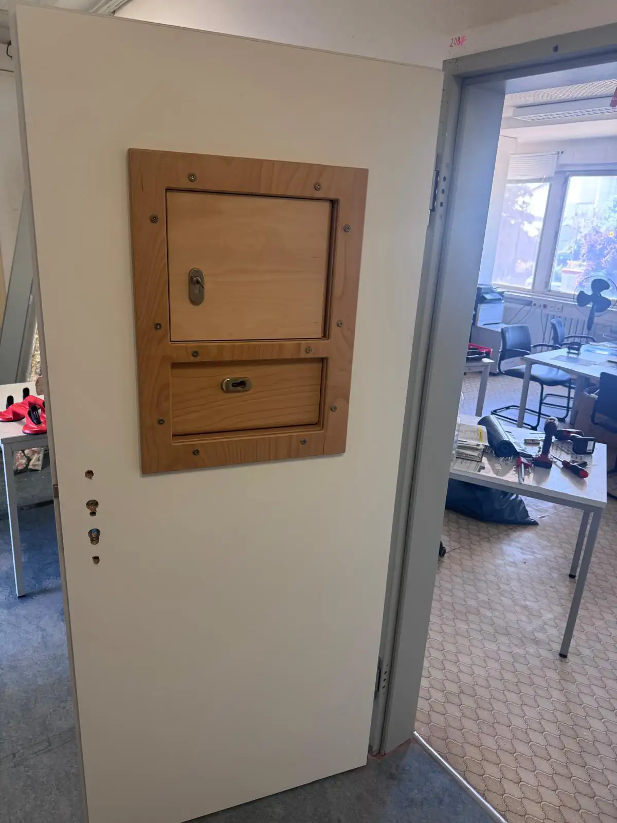 Wandseitige Durchreiche mit zwei abschließbaren Holzklappen neben der Sicherheitstür in einer Verwaltungseinrichtung in Magdeburg