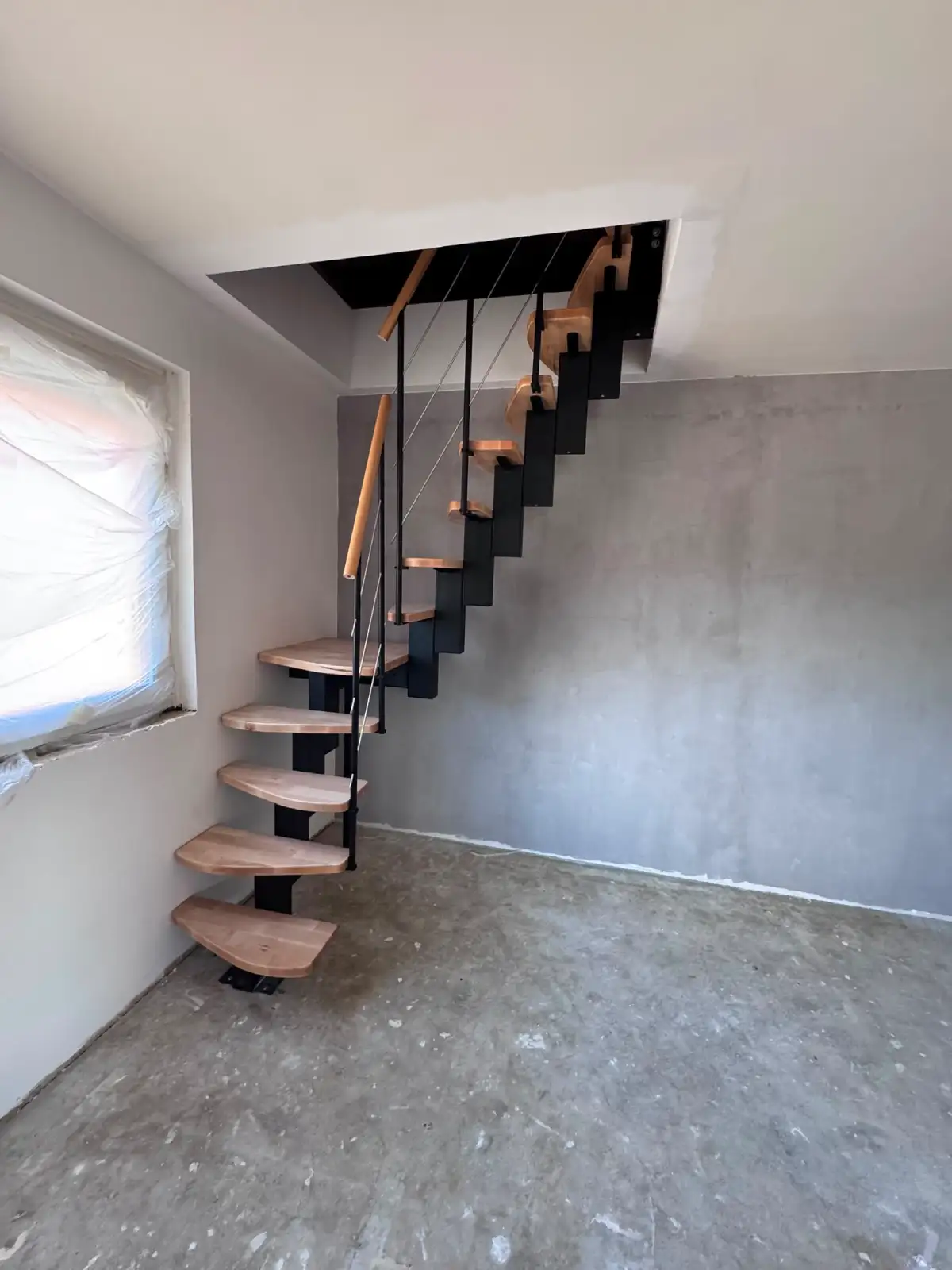 Fertig eingebaute Raumspartreppe mit schwarzer Stahlkonstruktion und Buchenstufen zum Dachgeschoss in Magdeburg