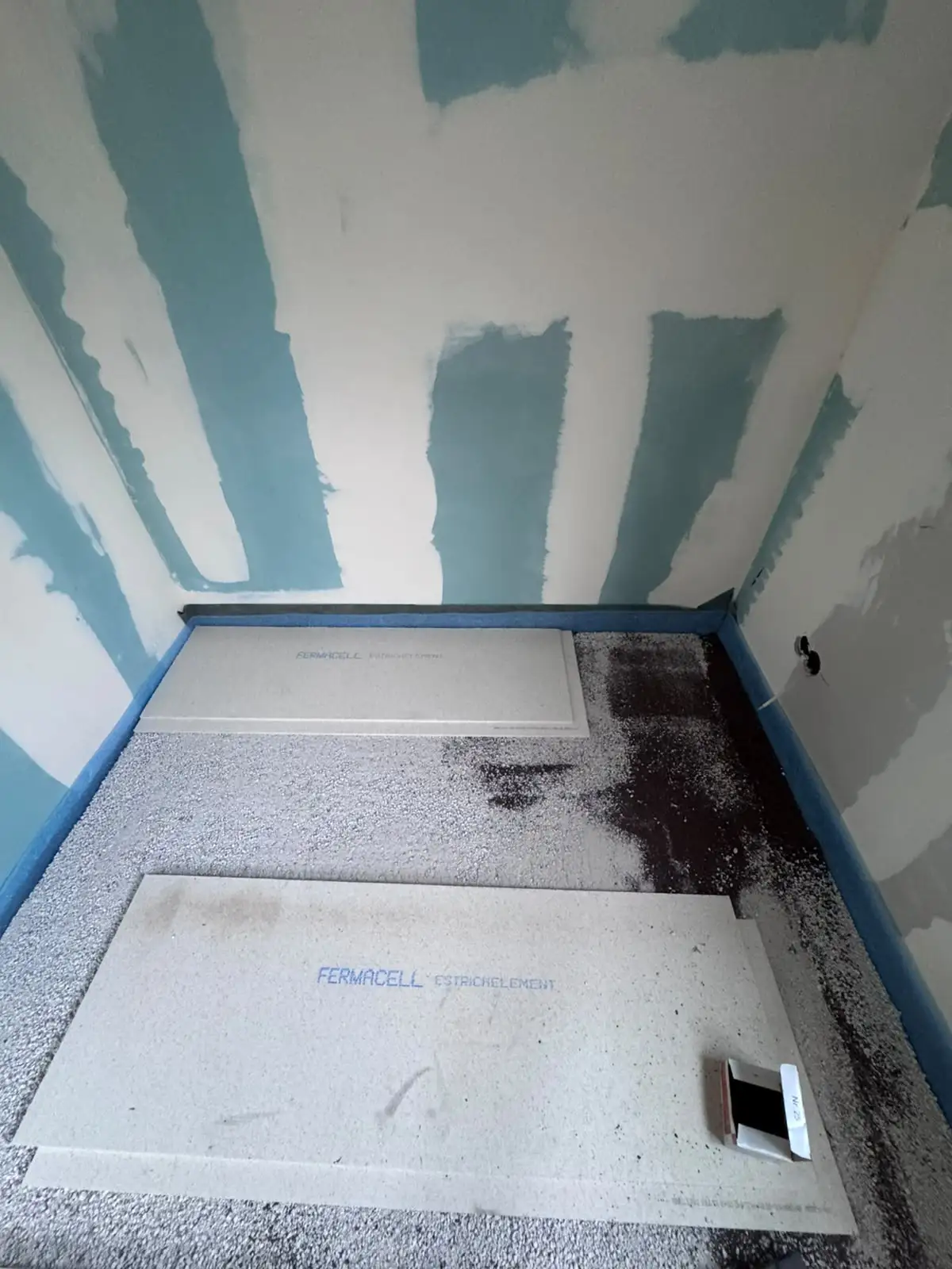 Erste Fermacell-Estrichelemente liegen im Eckbereich auf der Ausgleichsschüttung, blauer Randdämmstreifen an der Wand, Niederndodeleben